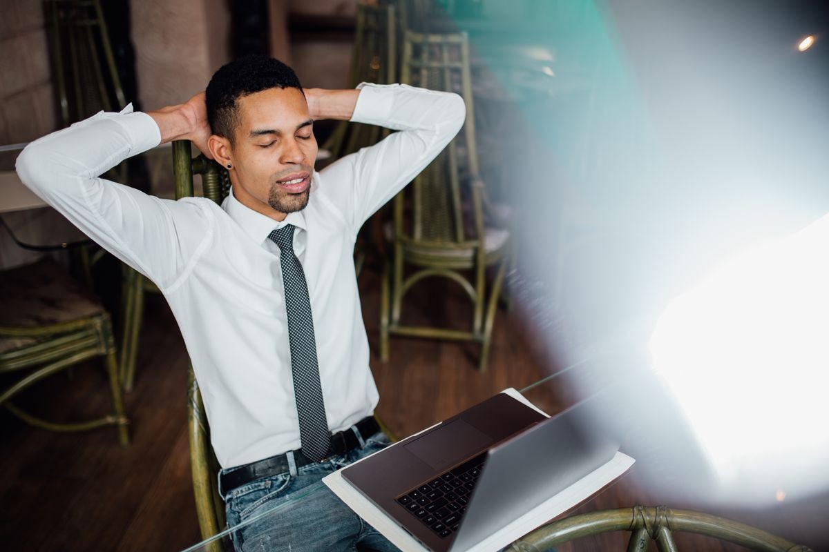 Satisfied businessman happy to finish work with laptop at coffe brake,  relaxing after hard working day in expectation of weekend leave, relaxed workday, no stress, in a white shirt, indoor, 