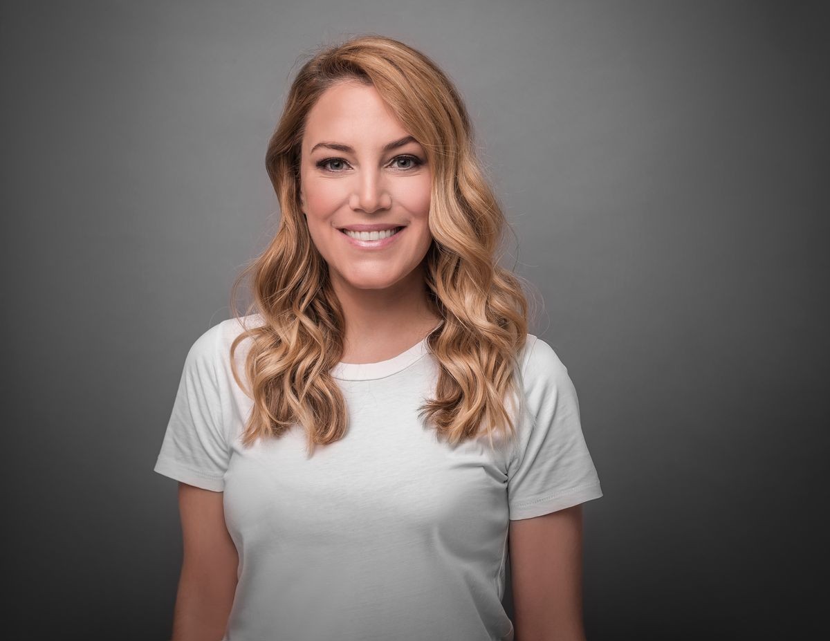 Beautiful blonde is smiling. Studio photo of a young attractive woman on a gray background.